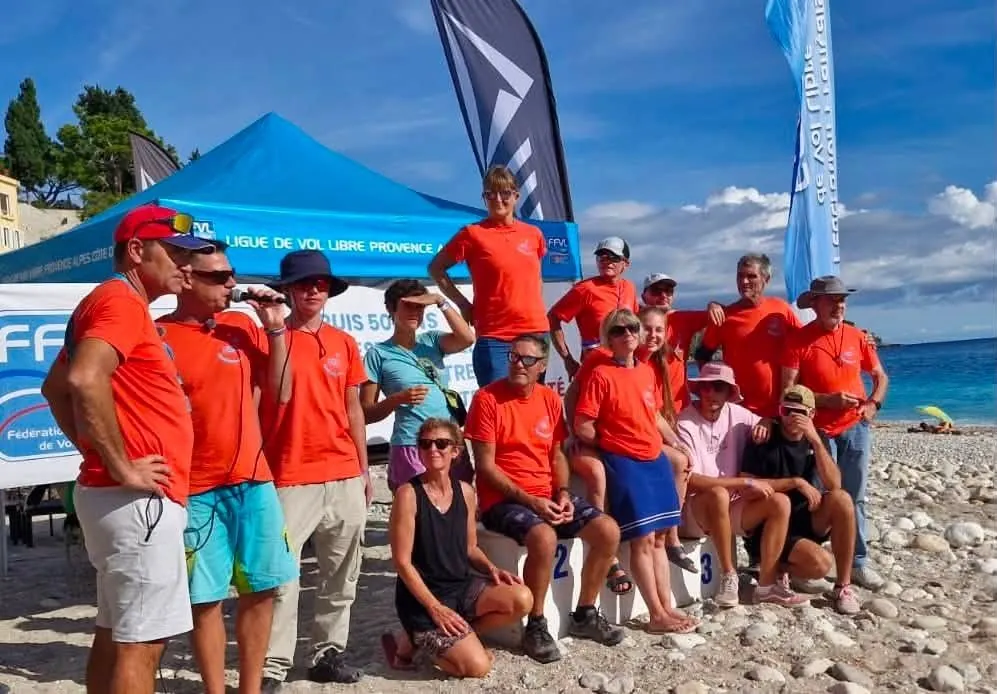 Les bénévoles de Roq'Acro en t-shirts orange réunis autour du podium sur la plage